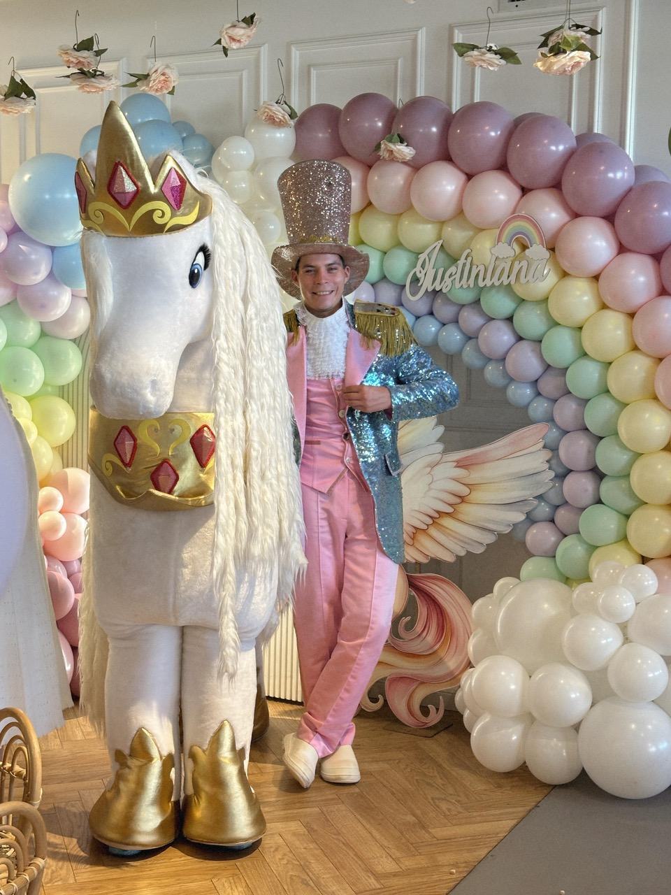 Mascota unicorn și animatorul la o petrecere cu arcadă de baloane pastel